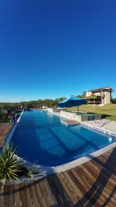 a large blue swimming pool with an umbrella at Cabañas Balcones de Nogolí II - San Luis in Hipólito Yrigoyen