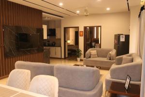 a living room with two couches and a tv at Designer Den two Bed apartment opposite to giga mall in Islamabad