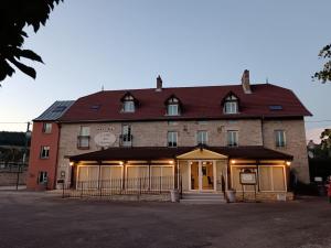 a large brick building with a clock on it at Logis Hôtel L'Orée des Charmes et son restaurant L'évYdenCe in Blaisy-Bas