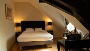 a bedroom with a bed and a chair in a attic at Logis Hôtel L'Orée des Charmes et son restaurant L'évYdenCe in Blaisy-Bas