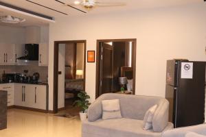 a living room with a couch and a kitchen at Designer Den two Bed apartment opposite to giga mall in Islamabad
