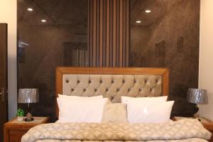 a bedroom with a large bed and two lamps at Designer Den two Bed apartment opposite to giga mall in Islamabad