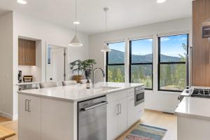 a kitchen with white cabinets and large windows at Bridger Bowl - Crosscut Hideaway in Bozeman