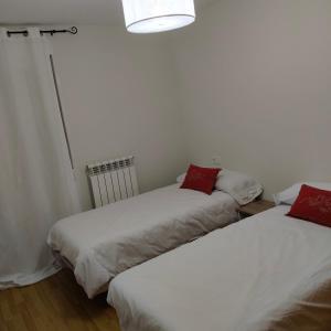 a room with two beds with white sheets and red pillows at Las heras apartamento in Medrano