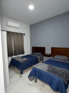 a room with two beds with blue sheets at los agaves lto in Loreto