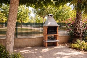 a brick oven sitting next to two trees at Casa Amor - "Pet Friendly - Piscina Privada - Playa - BBQ - Parking - Delta de l'Ebre - Riumar" in Riumar