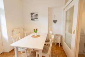 a white dining room with a white table and chairs at Stadtvilla Alpenliebe in Bad Reichenhall +9 photos