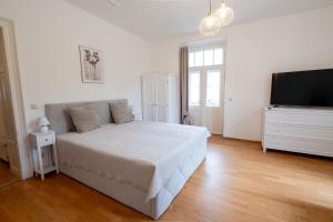a white bedroom with a bed and a flat screen tv at Stadtvilla Alpenliebe in Bad Reichenhall