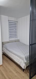 a bed in a white bedroom with a window at Apartman Bety in Brčko
