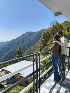 a man and a woman standing on a balcony looking at the mountains at Chill with pahadi in Lansdowne +33 photos