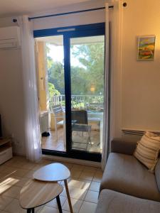 a living room with a couch and a sliding glass door at Coudou Beach T2 cosy à 2 pas de la mer in Six-Fours-les-Plages