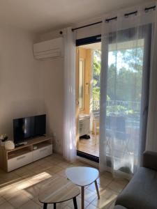 a living room with a couch and a tv and a table at Coudou Beach T2 cosy à 2 pas de la mer in Six-Fours-les-Plages
