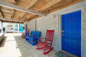 three red and blue chairs on a porch with a blue door at Sand Dollar Suites 2 in Carolina Beach
