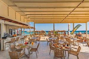 a restaurant on the beach with tables and chairs at Lotus Serenity Suites in Amoudara Herakliou