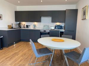 a kitchen with a white table and blue chairs at Top-end penthouse with sea views and free parking in Ramsgate