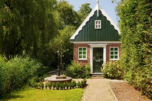 a small red brick house with a green roof at B&B Saense huisje in Assendelft