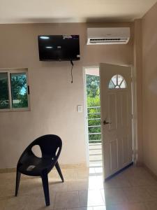 a black chair sitting in a room with a television on the wall at Rivera Solea in Llano de Los Patos