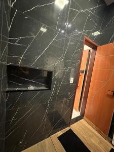 a bathroom with a black marble wall and a door at Flat jk 04 térreo in Juazeiro do Norte +18 photos
