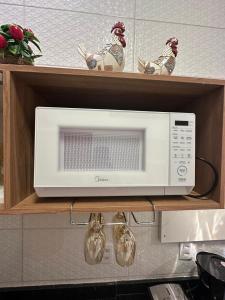 a microwave on a shelf in a kitchen at Flat jk 04 térreo in Juazeiro do Norte