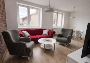 a living room with a red couch and two chairs at Apartmány Bozen Lednice in Lednice