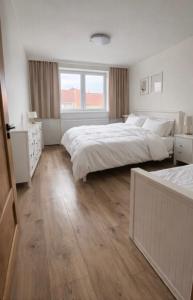 a white bedroom with two beds and a window at Apartmány Bozen Lednice in Lednice