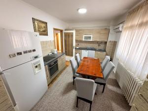a kitchen with a wooden table and a white refrigerator at Villa Igman in Hrasnica