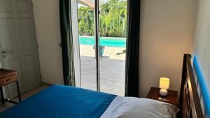 a bedroom with a bed and a view of a pool at Tropical Suite Direct Pool Access & Garden View in Baie-Mahault