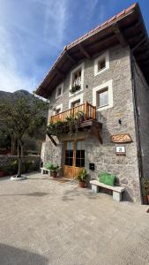 a large stone building with a balcony and benches at Casa Candina in Castro-Urdiales