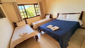 a bedroom with two beds and a window at Itaipava Cama e Café in Itaipava