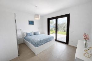 a white bedroom with a bed and a window at La Casetta in Toscolano Maderno
