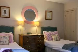a bedroom with two beds and a dresser and a mirror at Spacious cottage - walk to Crieff in Crieff
