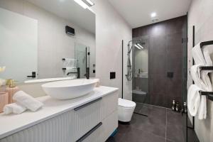 a white bathroom with a sink and a shower at Haven on the Lake Front in Frankton +10 photos