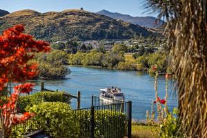 a boat on a river with mountains in the background at Haven on the Lake Front in Frankton