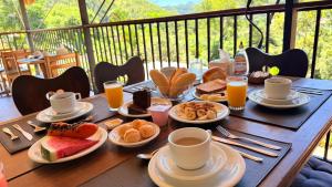 a wooden table with plates of breakfast food on it at Itaipava Cama e Café in Itaipava +32 photos