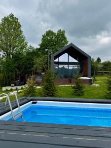 a swimming pool in front of a house at Stodola Slavsko котедж з чаном-джакузі in Slavske