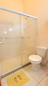 a bathroom with a shower with a toilet and a rug at Itaipava Cama e Café in Itaipava