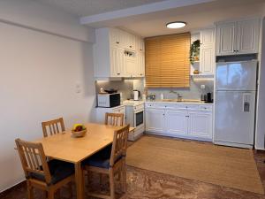 a kitchen with white cabinets and a wooden table with chairs at Seashore Happiness Apartments in Porto Rafti