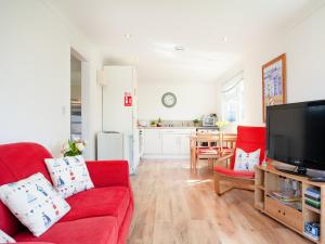 a living room with a red couch and a flat screen tv at Lodge 133 - Uk43196 in Saint Merryn