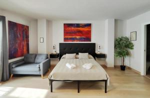a bedroom with a bed and a couch and paintings at Suite imperial Muralla de Lugo 2.2 in Lugo