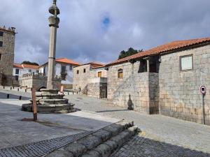 a street with a stone building and a light pole at Casa da Figueira in Aguiar da Beira