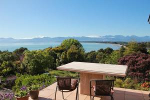 Ein Tisch und Stühle auf einer Terrasse mit Blick auf einen See in der Unterkunft Seascapes in Mapua