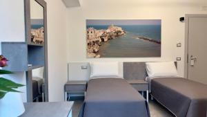 two beds in a room with a view of the ocean at Vesta Motel in Vieste
