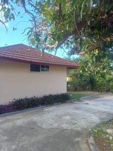 a white house with a tree next to a driveway at Tambell Haven in Runaway Bay