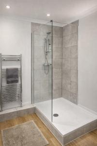 a shower with a glass door in a bathroom at Mango Tree Apartment - Near Leisure Park & Station in Cambridge