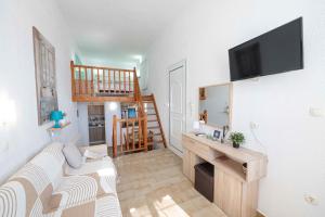 a living room with a couch and a tv on a wall at Rania Bella Vista Studios in Poros