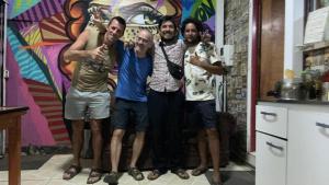 four men posing for a picture in front of a wall at Backpackers House - Near The Airport in Santiago