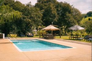 a swimming pool with an umbrella and tables and chairs at Monakó Cabanas in Bragança Paulista