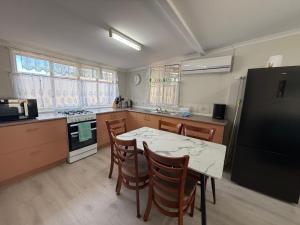 a kitchen with a table and chairs and a black refrigerator at Hideaway on King in Urangan +5 photos