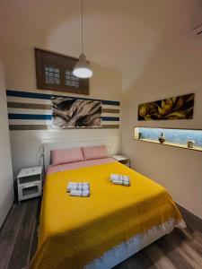 a bedroom with a yellow bed with two towels on it at La Corte di Noto in Noto