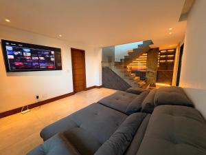 a living room with a large couch and a tv at Casa 05 Monte Boa Vista - Casa de Luxo na Serra com Sauna e 4 Suítes in Teresópolis